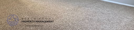 A carpeted room with a sliding glass door and a logo for Beach Front Property Management.